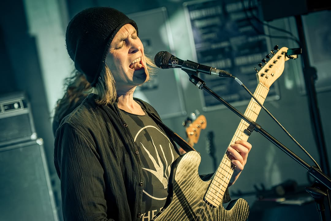 Forkalyst live: singer and guitarist Laurenz passionately singing into the microphone with his eyes closed.